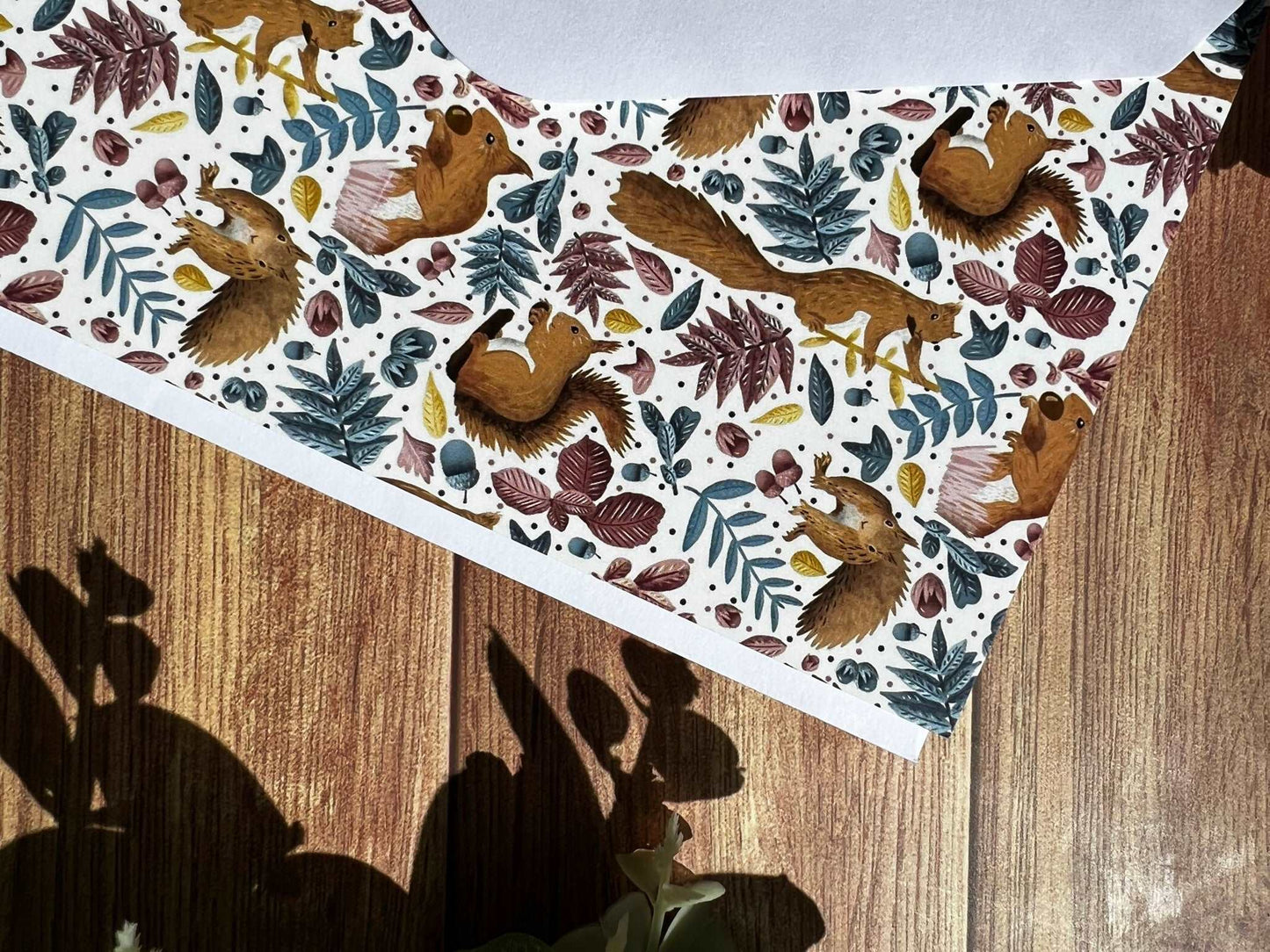 Closeup of the red squirrel pattern on a small greetings card with the envelope on a wooden surface, ideal for a red squirrel lovers birthday