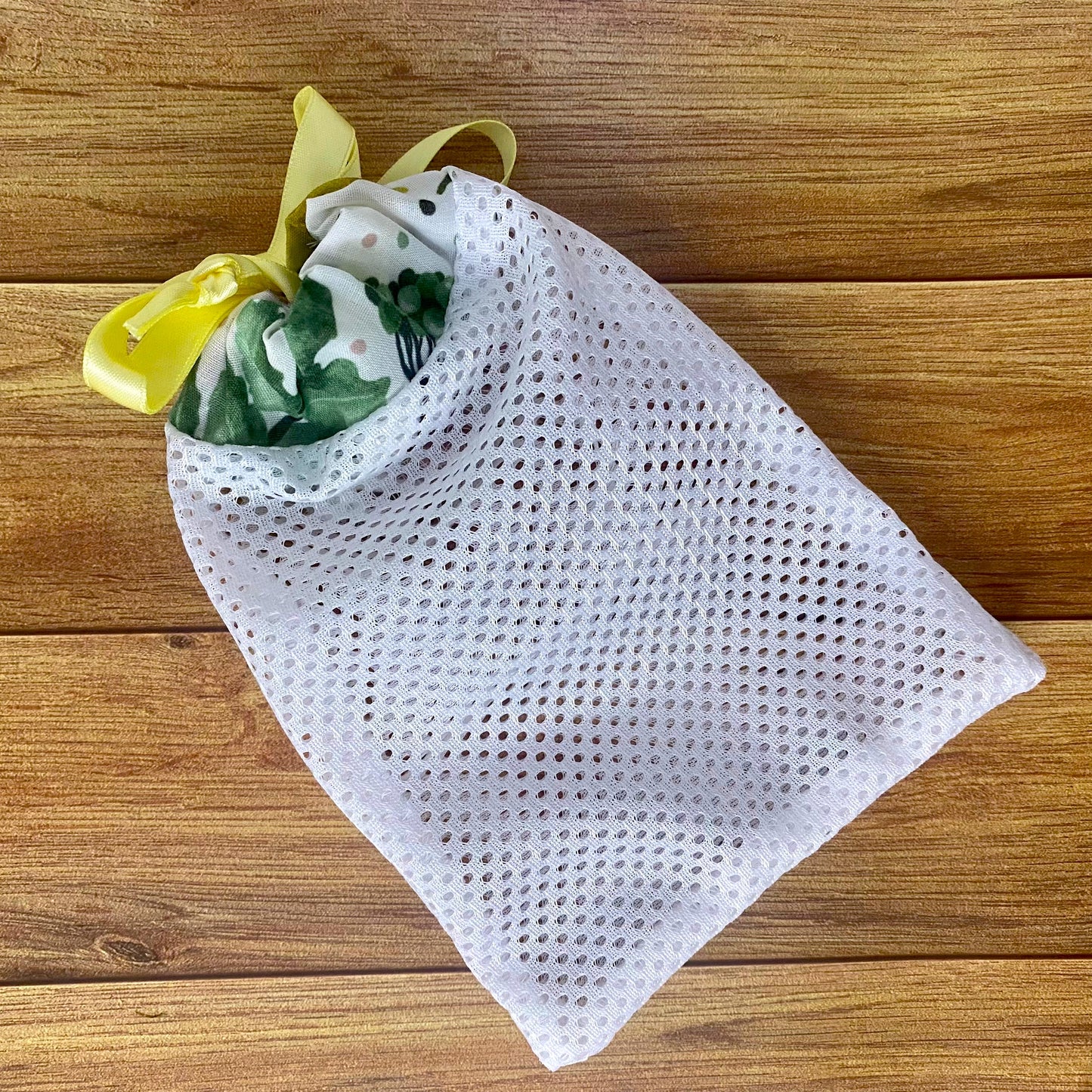 pretty foliage patterned washbag with yellow ribbon sat on wooden backdrop