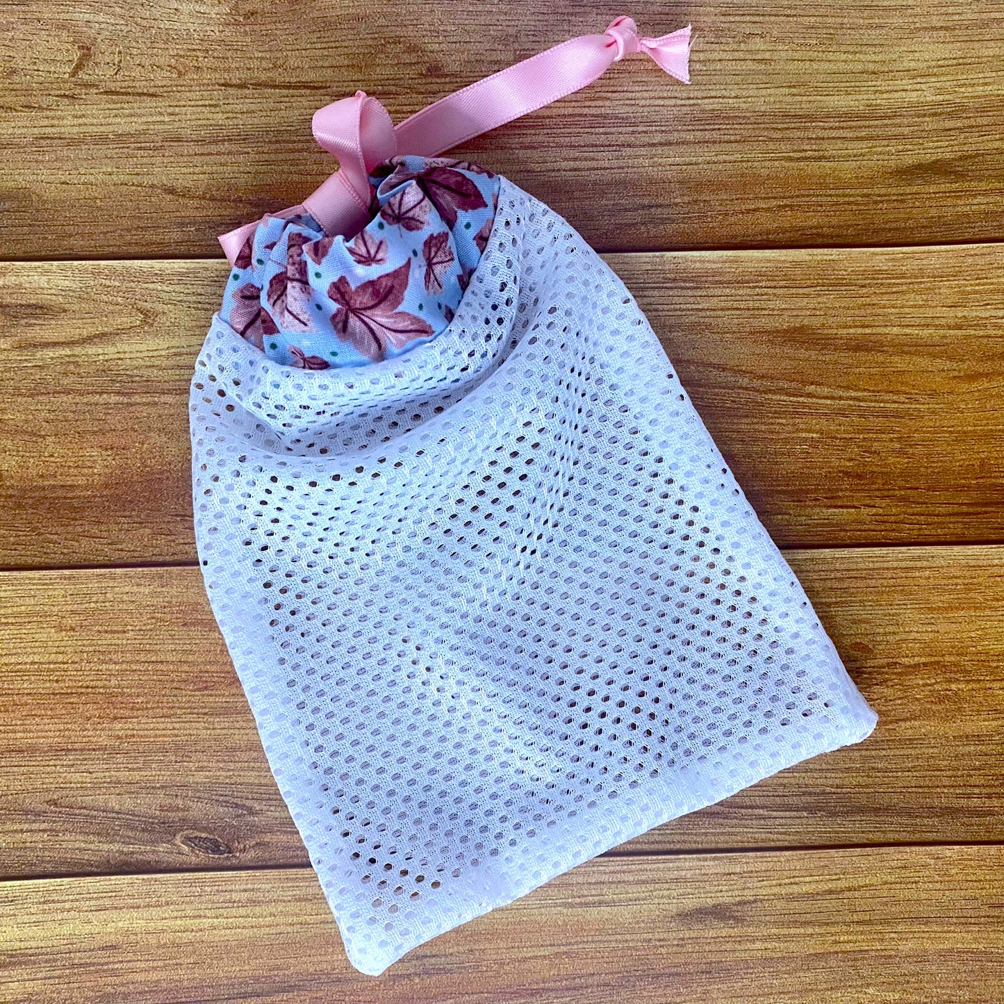 pink leafy patterned washbag on a wooden background