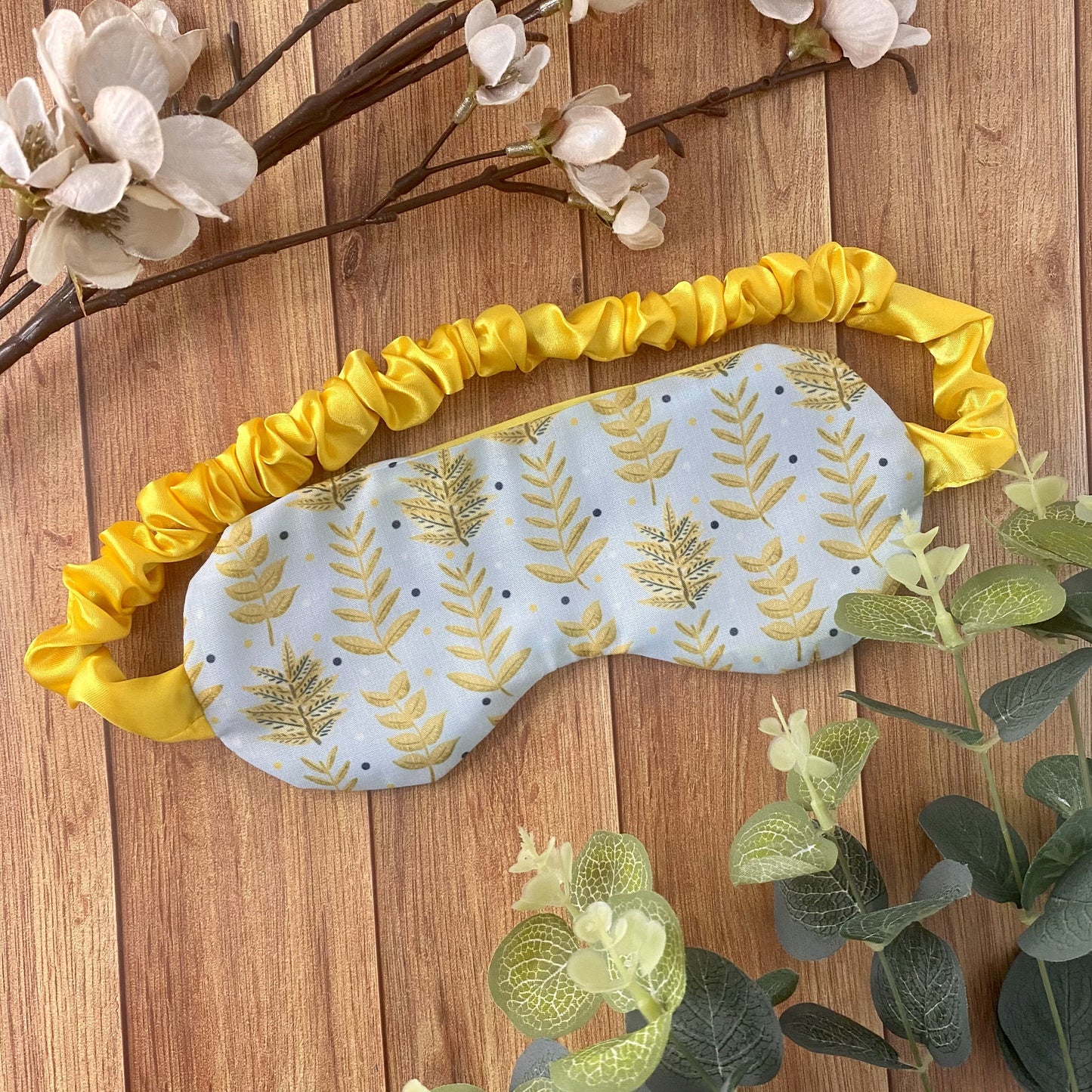 yellow foliage sleepmask amongst foliage on a wooden surface