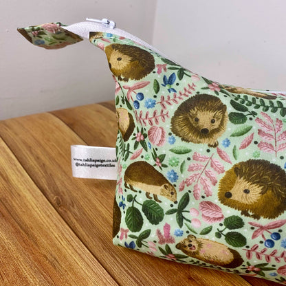 closeup photograph of the side of the hedgehog patterned makeup bag to show the shape of the sides. Wooden background behind.