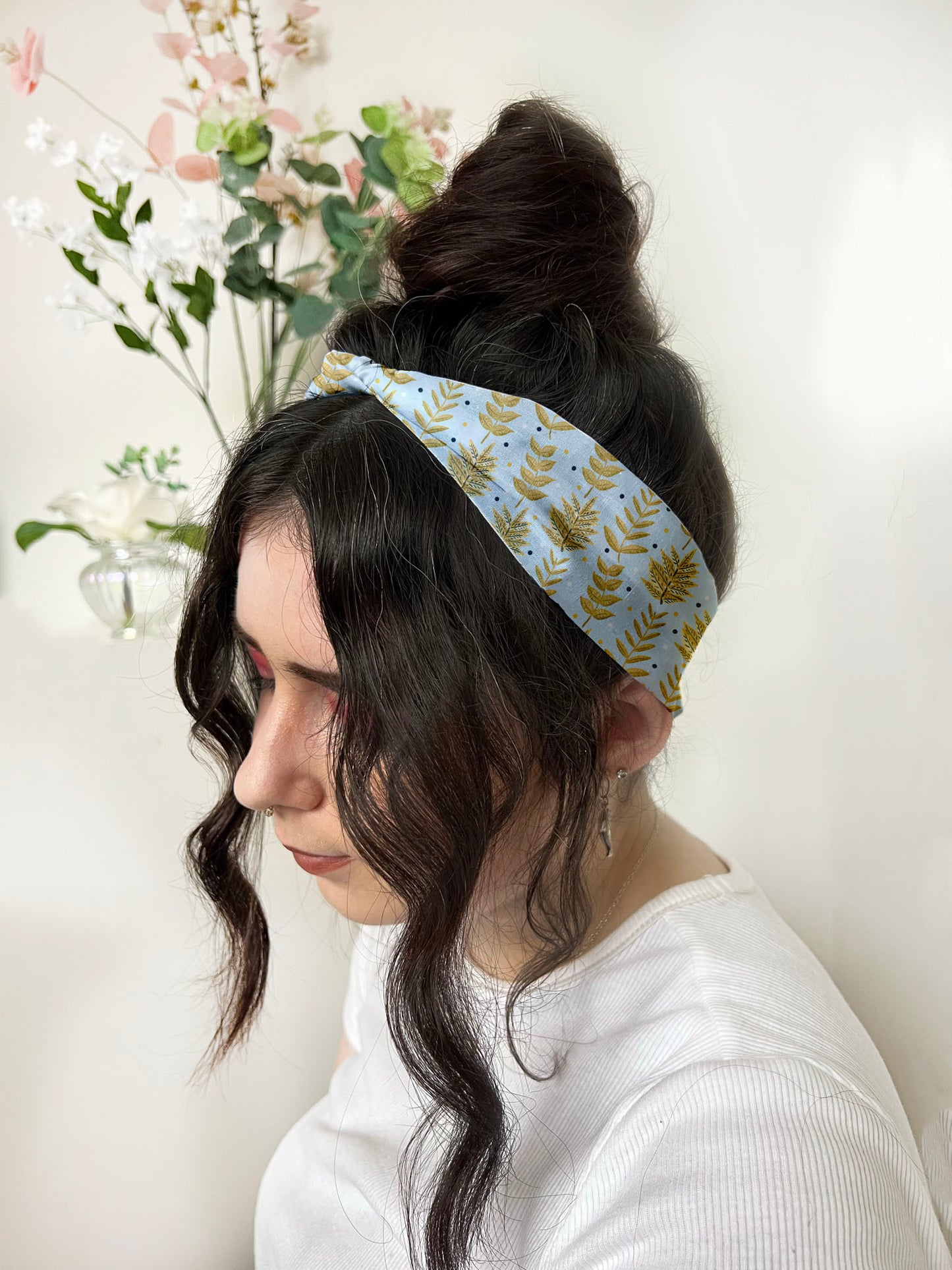 dark haired girl wears yellow foliage patterned headband with high bun