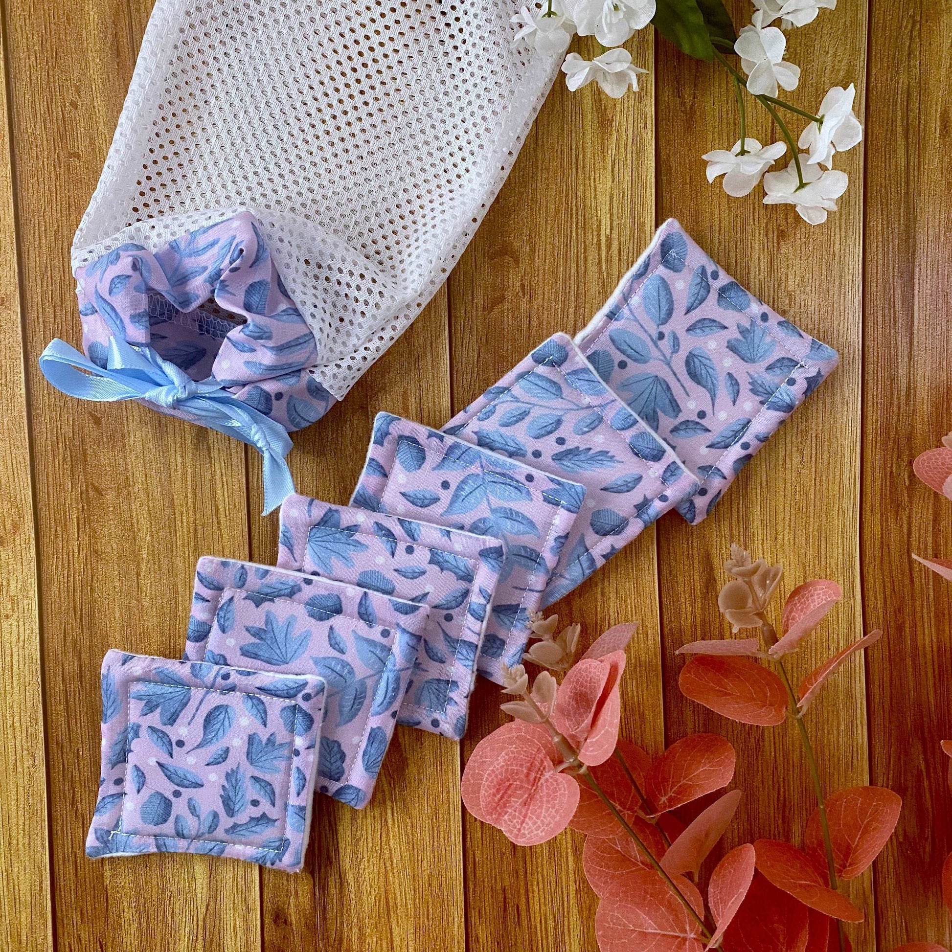 six reusable skincare pads and washbag on wood background
