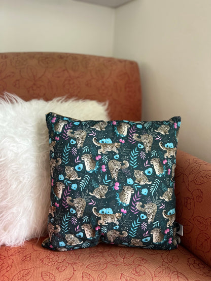 Shop wild animal gifts with this snow leopard cushion cover, in a deep navy colour sat on a pink armchair.