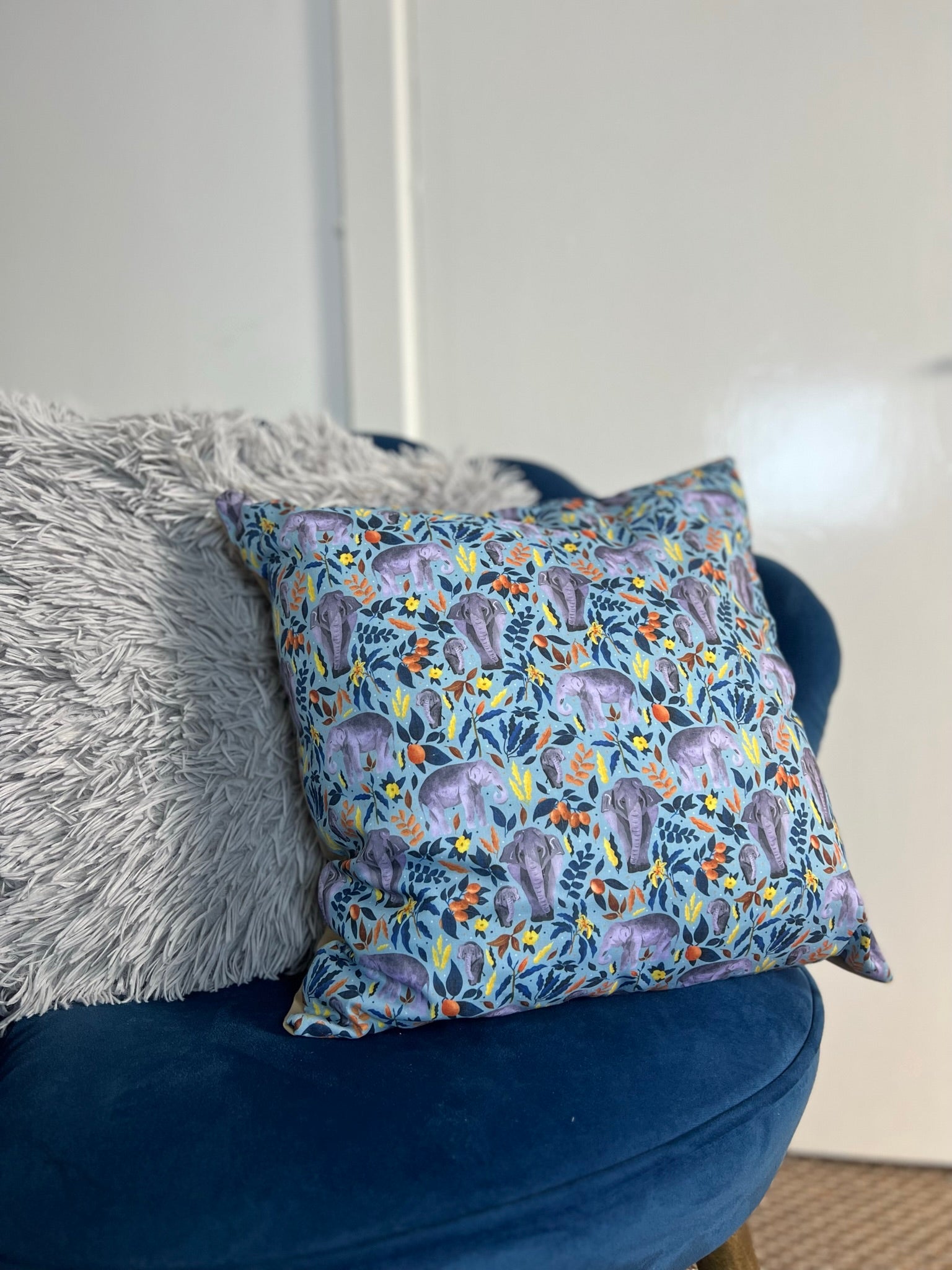an elephant decorative cushion on a blue armchair, an excellent gift for an elephant lover and great for sofa decor