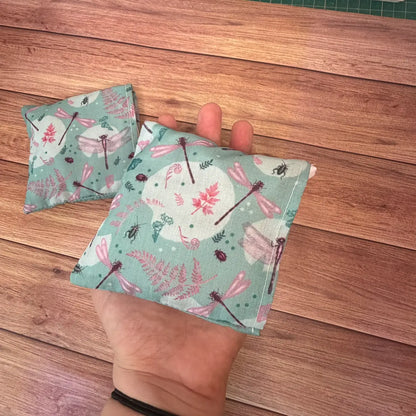 Microwaveable reusable hand warmers decorated with original dragonfly artwork.

