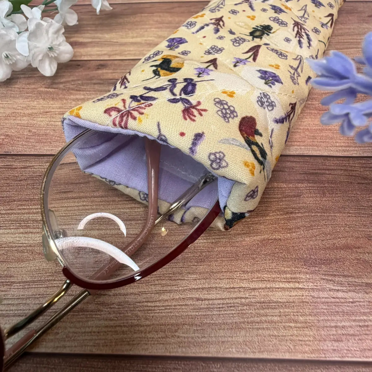 Quilted fabric spectacle holder featuring a bee pattern and hook-and-loop fastening.
