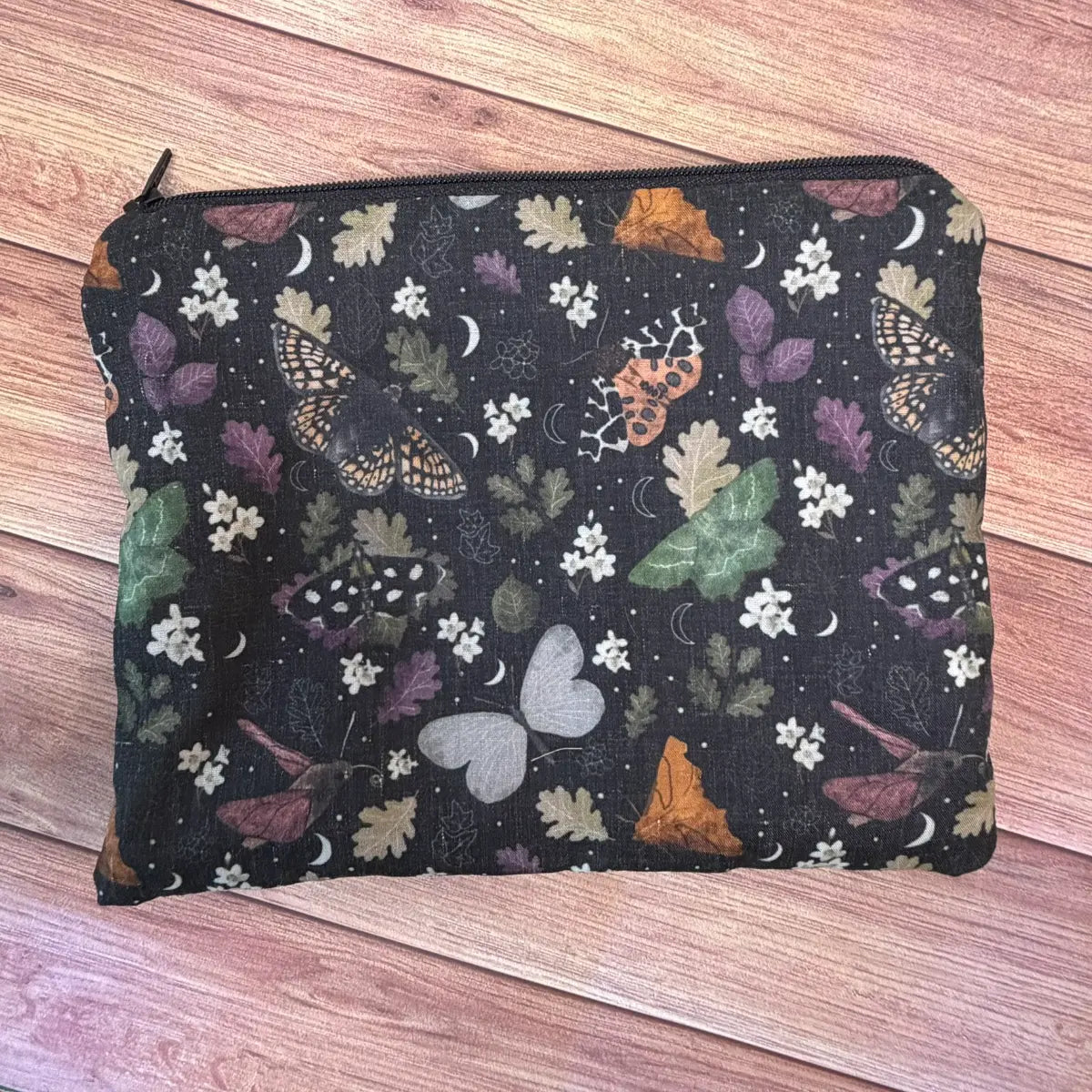 Compact moth cosmetic bag featuring original illustrated artwork, ideal for storing makeup and small accessories.
