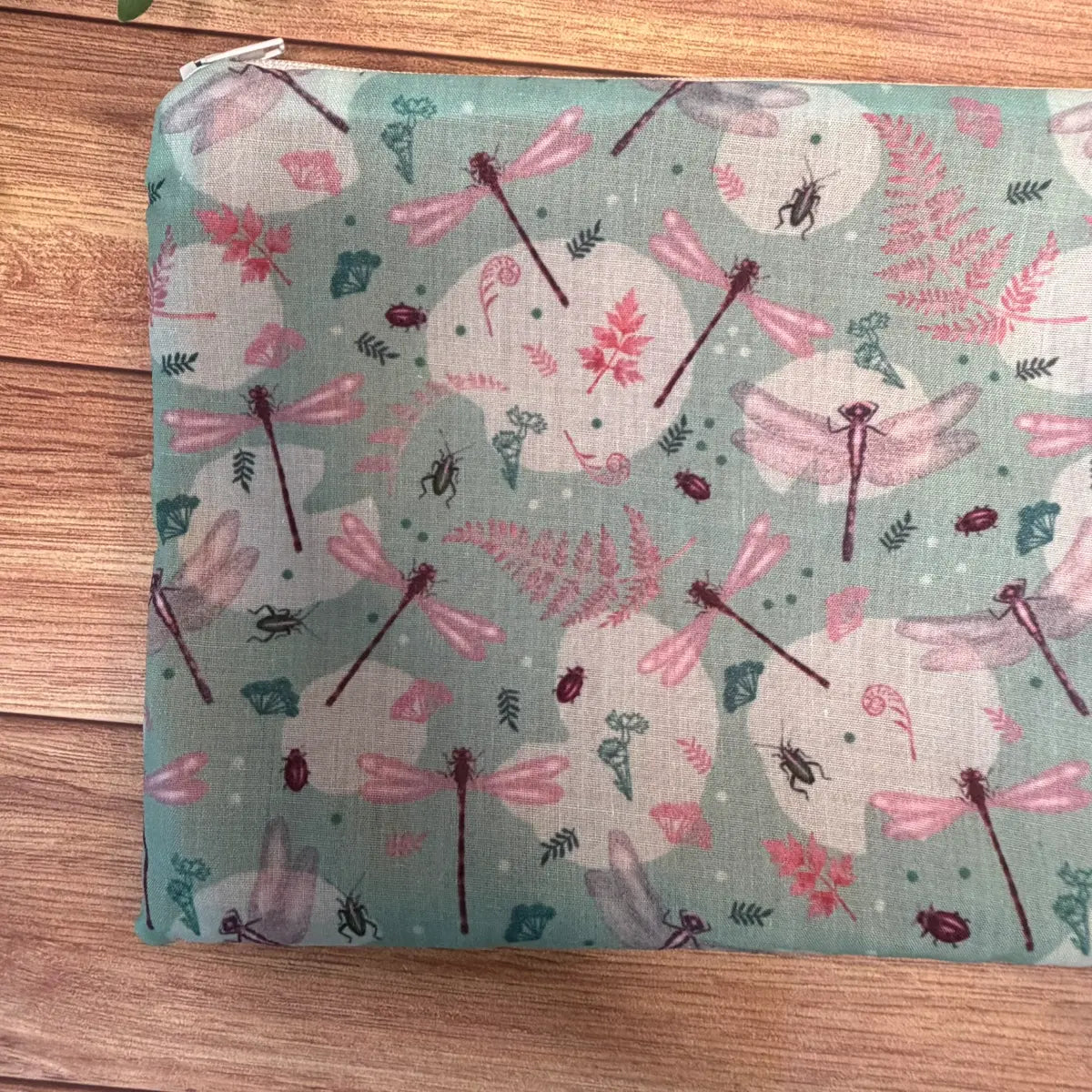 Fabric cosmetic pouch with a repeating illustrated dragonfly pattern.
