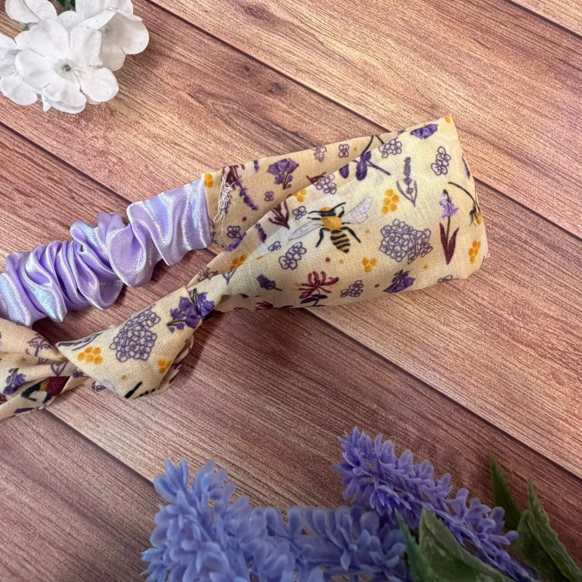 Fabric hairband decorated with a repeating bee pattern.
