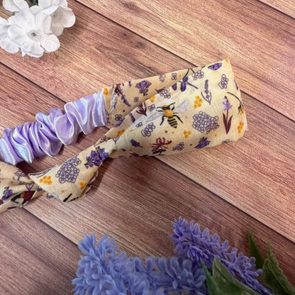 Fabric hairband decorated with a repeating bee pattern.
