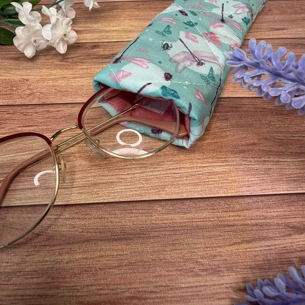 Quilted fabric glasses pouch featuring a dragonfly pattern and secure fastening.
