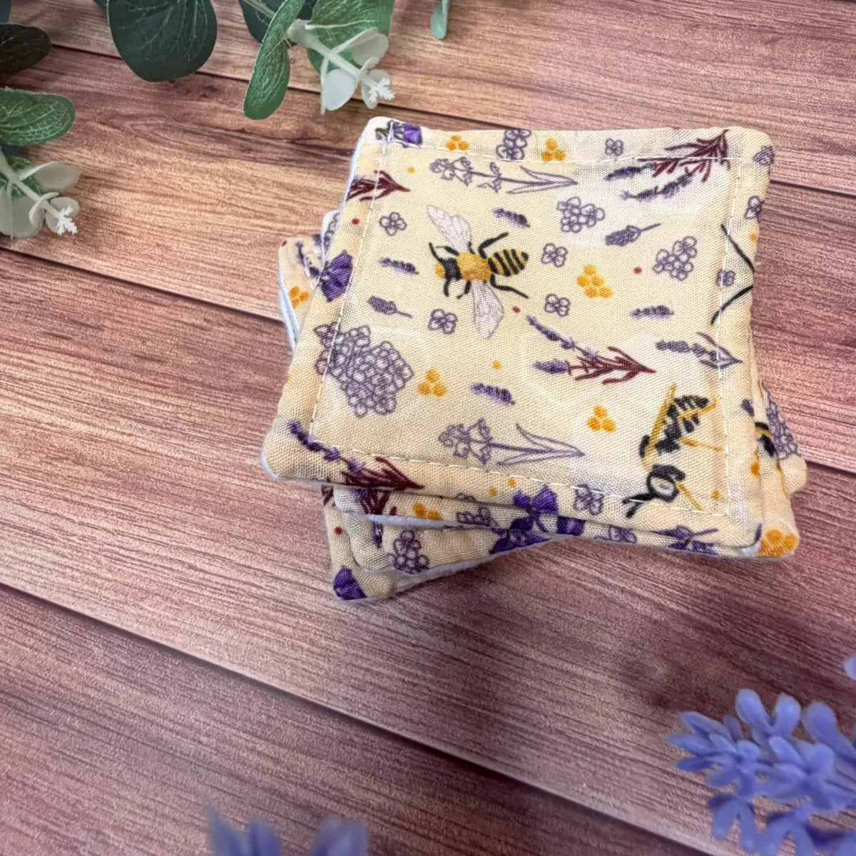 Reusable makeup remover pads with white brushed cotton surfaces and bee patterned backings.
