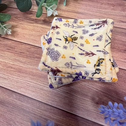 Reusable makeup remover pads with white brushed cotton surfaces and bee patterned backings.
