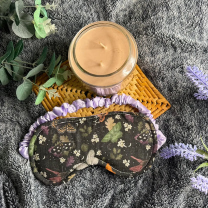 Fabric sleeping eye mask with a repeating moth pattern and darker design.
