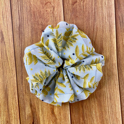yellow foliage on blue background pattern on a fabric scrunchie, sat on a wood background
