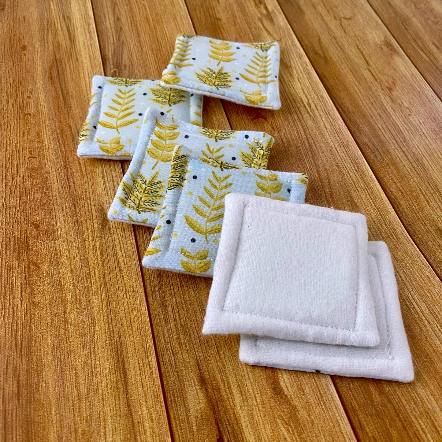 reusable skincare pads shown on a wooden background with two turned over to show the white brushed cotton side