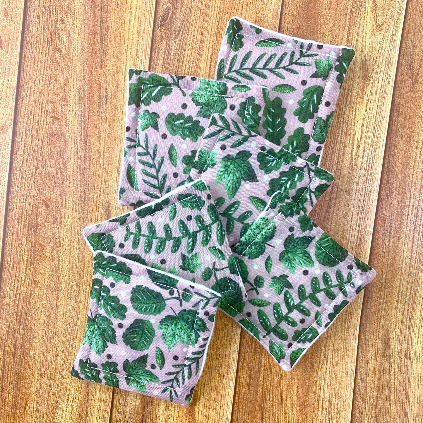 green foliage patterned reusable skincare pads on wooden surface