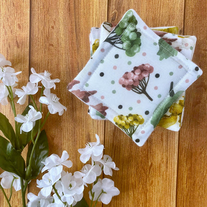 Pretty foliage patterned skincare pads on a wooden backdrop with flowers around it