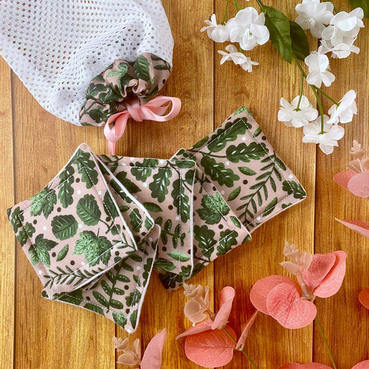 green foliage patterned reusable skincare pads and washbag on wooden surface with flowers and leaves around them