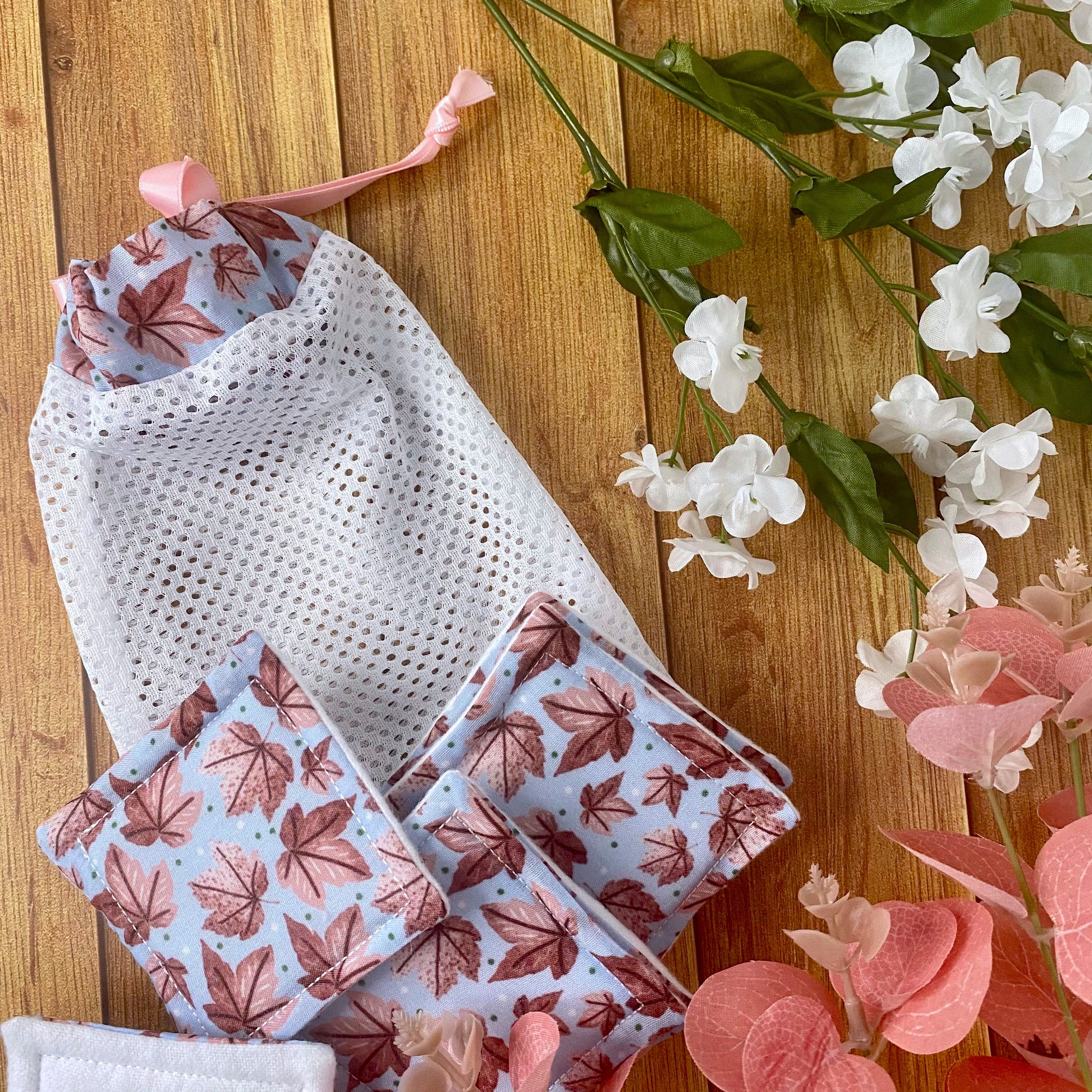 pink leafy patterned reusable skincare pads and washbag on wood surface