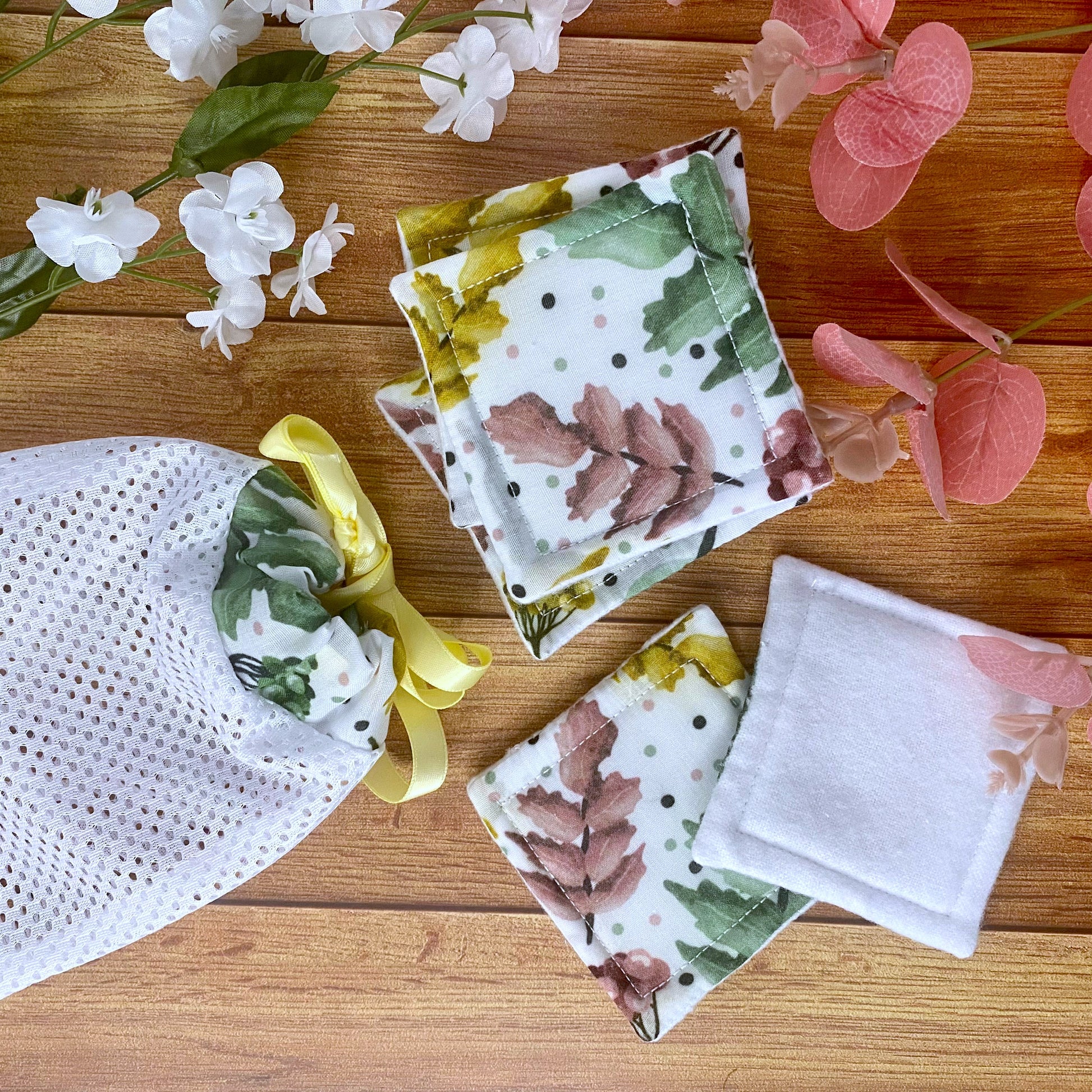 reusable skincare pads and washbag matching with pretty foliage pattern on them, on a wooden background with foliage around