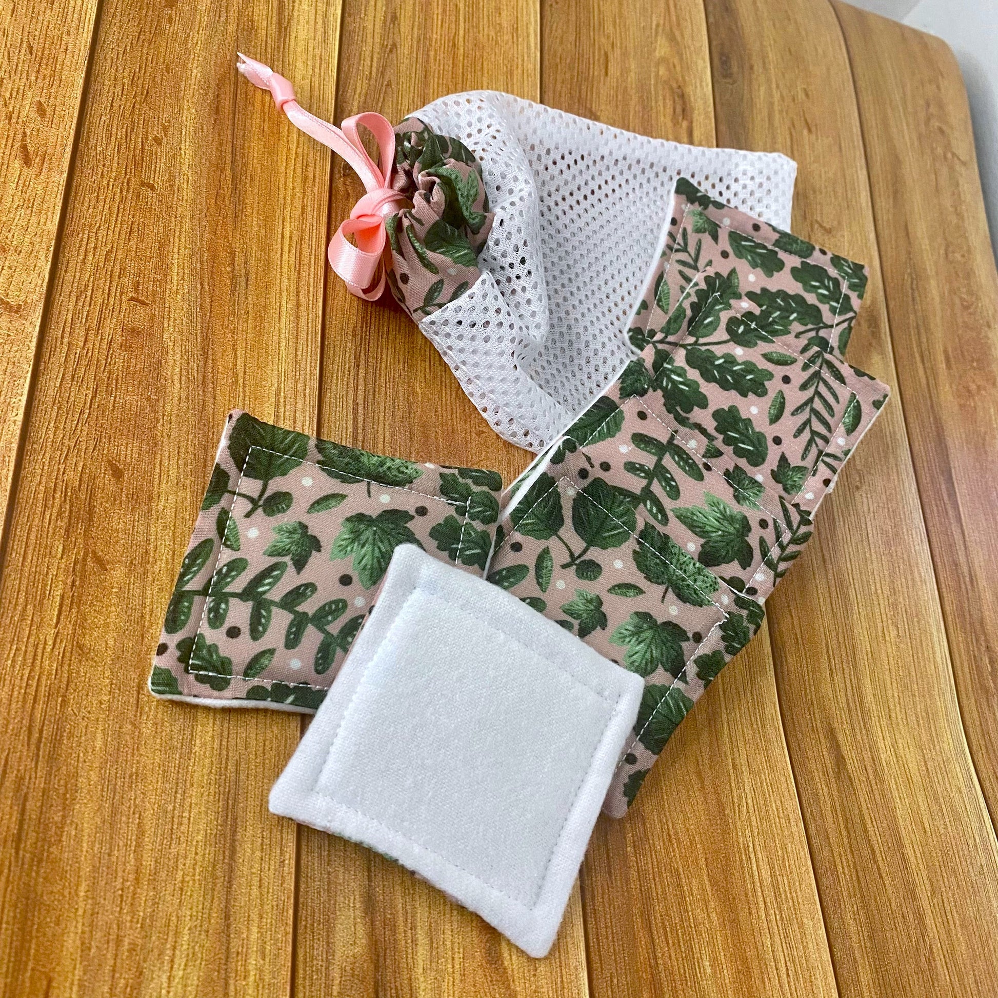 green foliage patterned reusable skincare pads and washbag on wooden surface