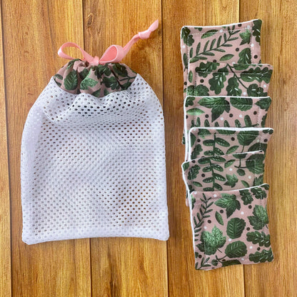six reusable makeup removal pads and matching washbag with the green foliage pattern, all on a wooden surface