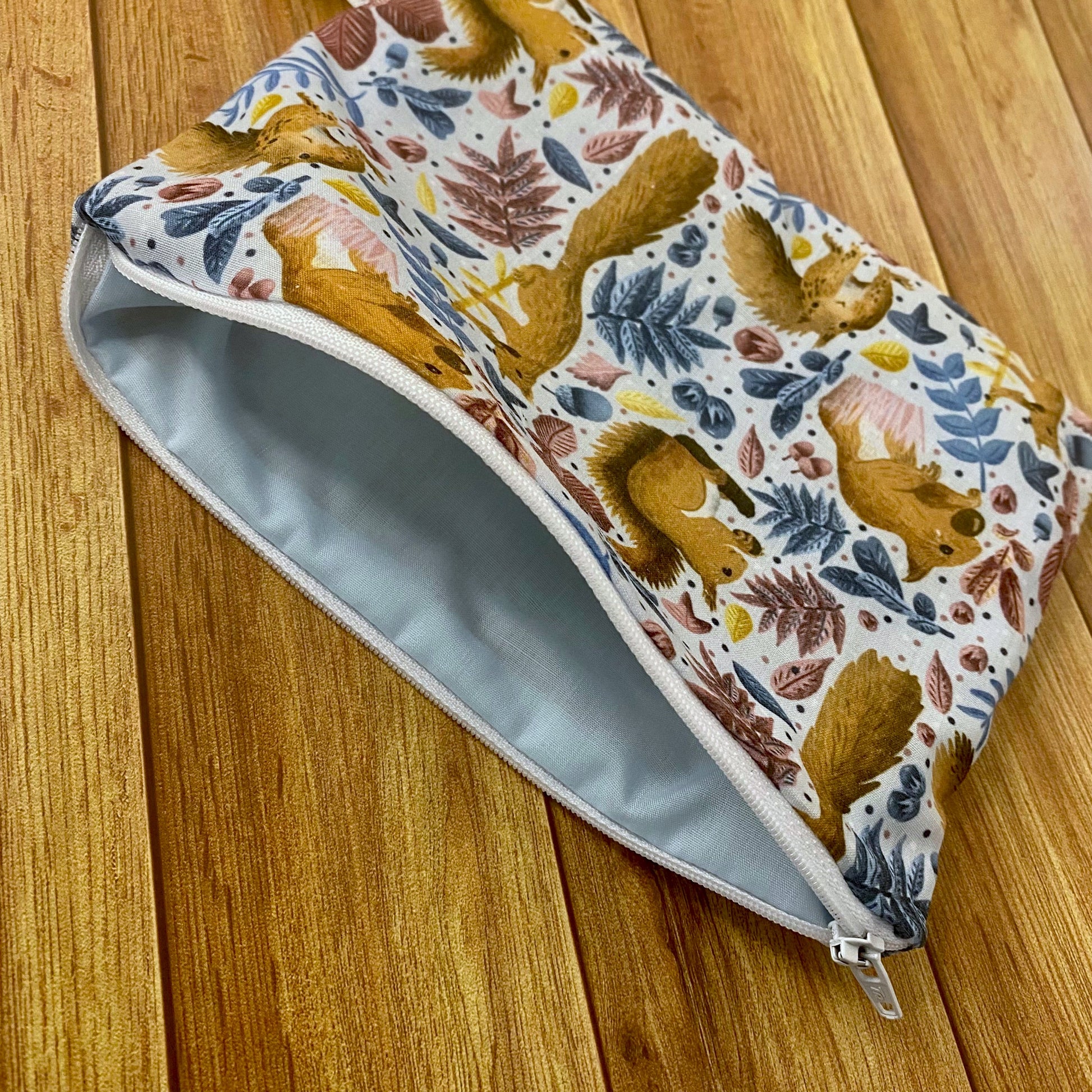 photograph of an open pouch with the red squirrel surface pattern design on it, the storage pouch is an ideal red squirrel gift and can be used as a makeup bag for handbag use.