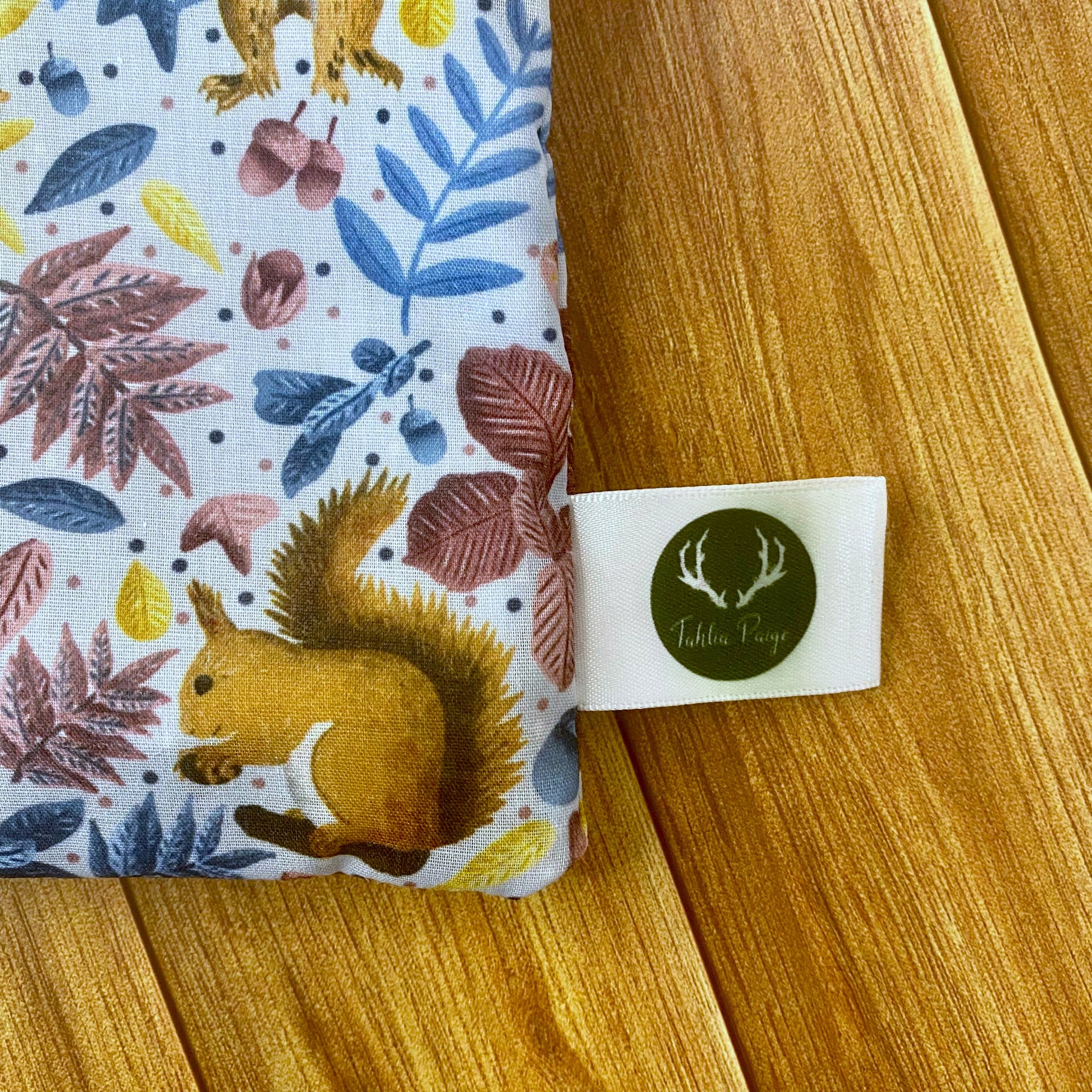 Closeup photograph of the corner of the red squirrel patterned pouch showing the Tahlia Paige label