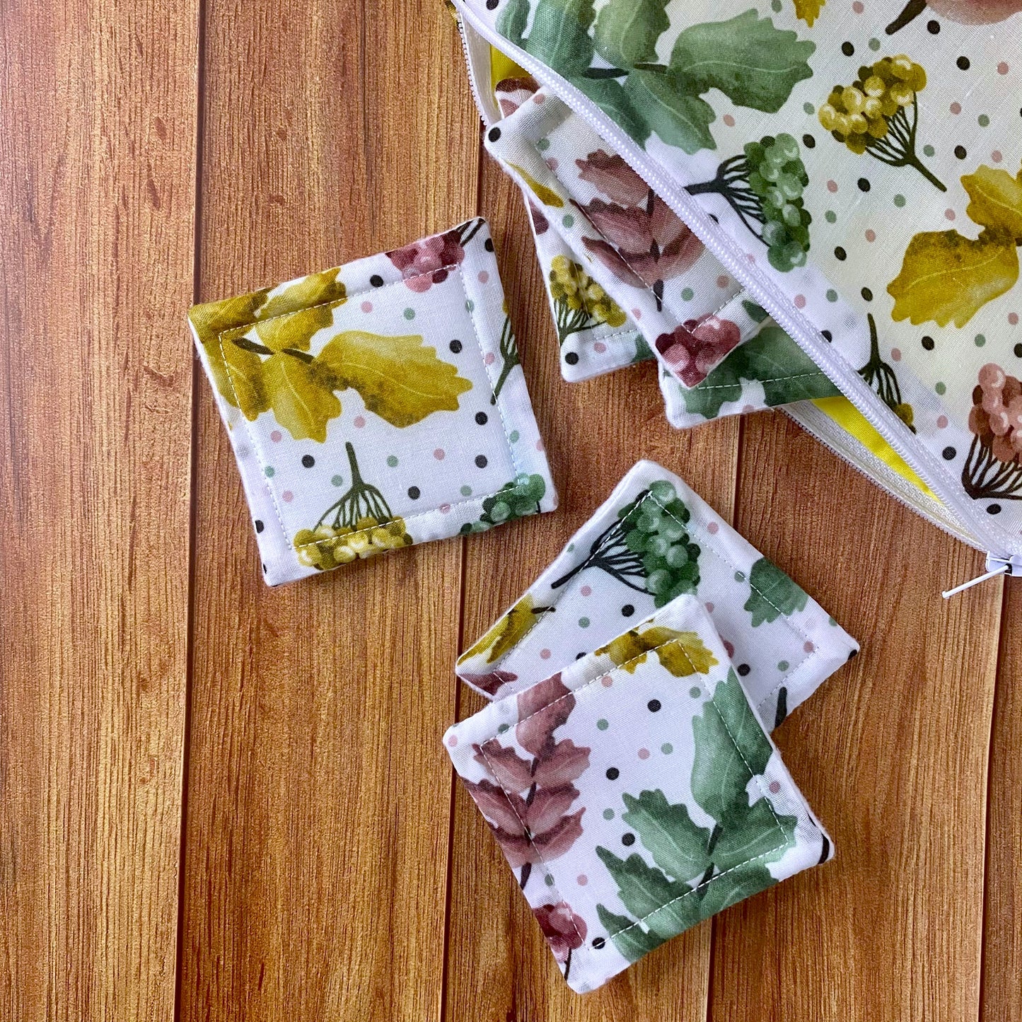 pretty foliage patterned reusable skincare pads spilling out of pouch on wooden background