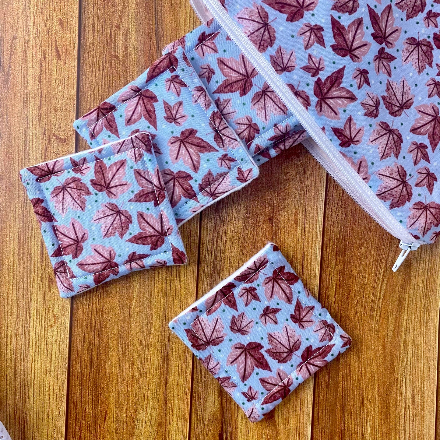 reusable skincare pads spilling out of a pouch with the pink leafy pattern design on them