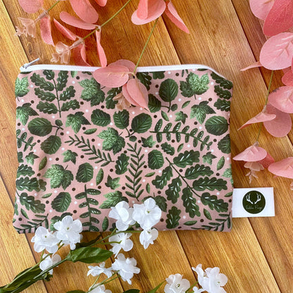 green foliage patterned pouch amongst flowers and foliage on a wooden surface