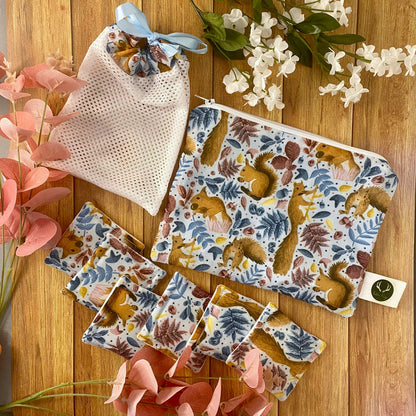 red squirrel patterned giftset including pouch, washbag and reusable makeup removal pads on wood surface with foliage around