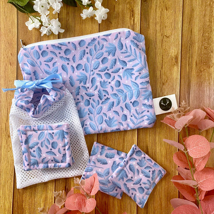 blue foliage pouch, reusable skincare pads and washbag arranged on a wooden background with foliage around them