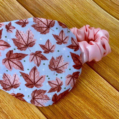 closeup of pink leafy patterned sleepmask with wooden background behind it
