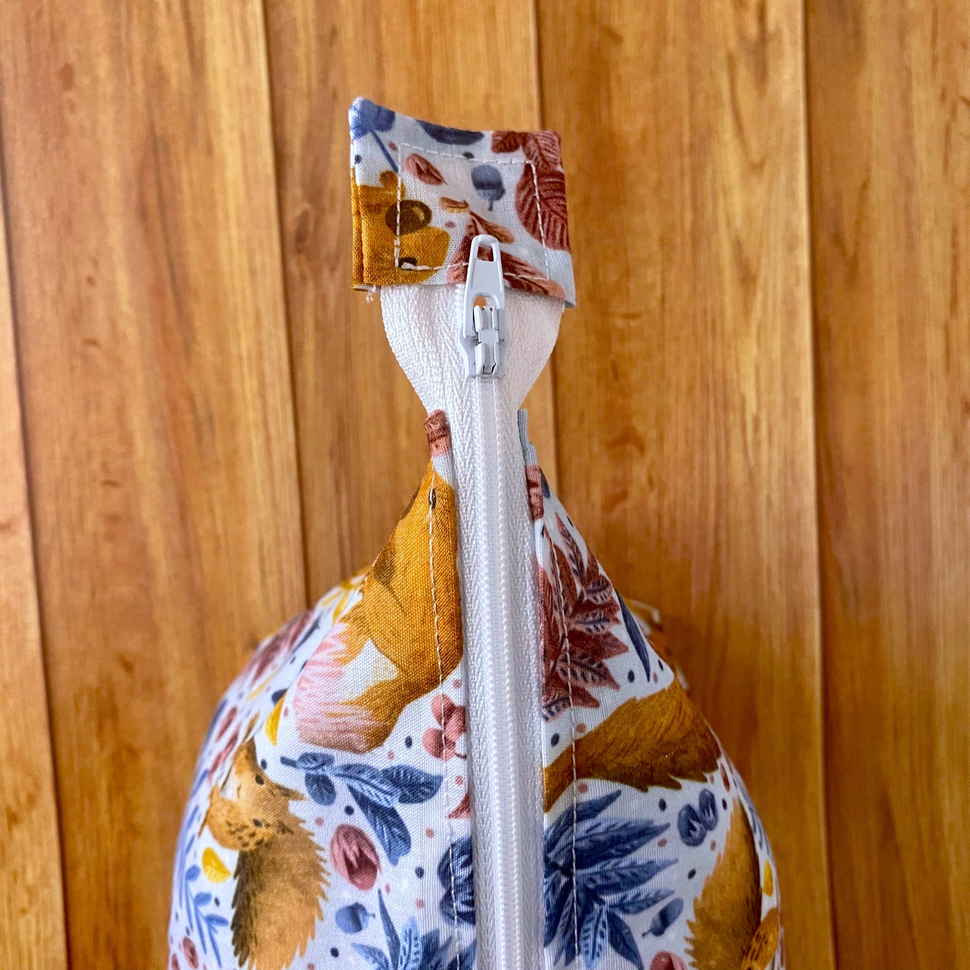 Closeup of the red squirrel patterned makeup bag zip from a birds eye view showing the pattern on the bag and the white zip.