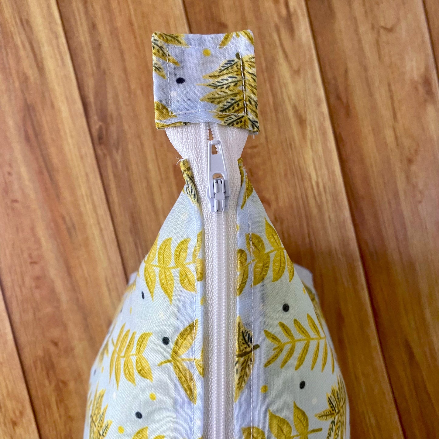 Closeup birds eye view of the yellow foliage patterned makeup bag.