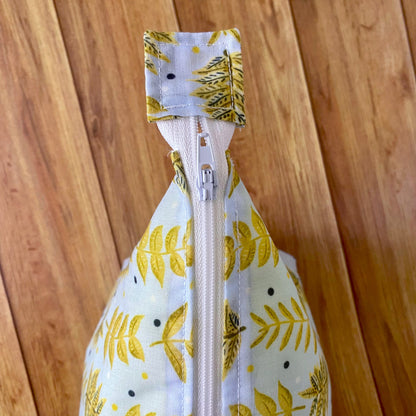 Closeup birds eye view of the yellow foliage patterned makeup bag.