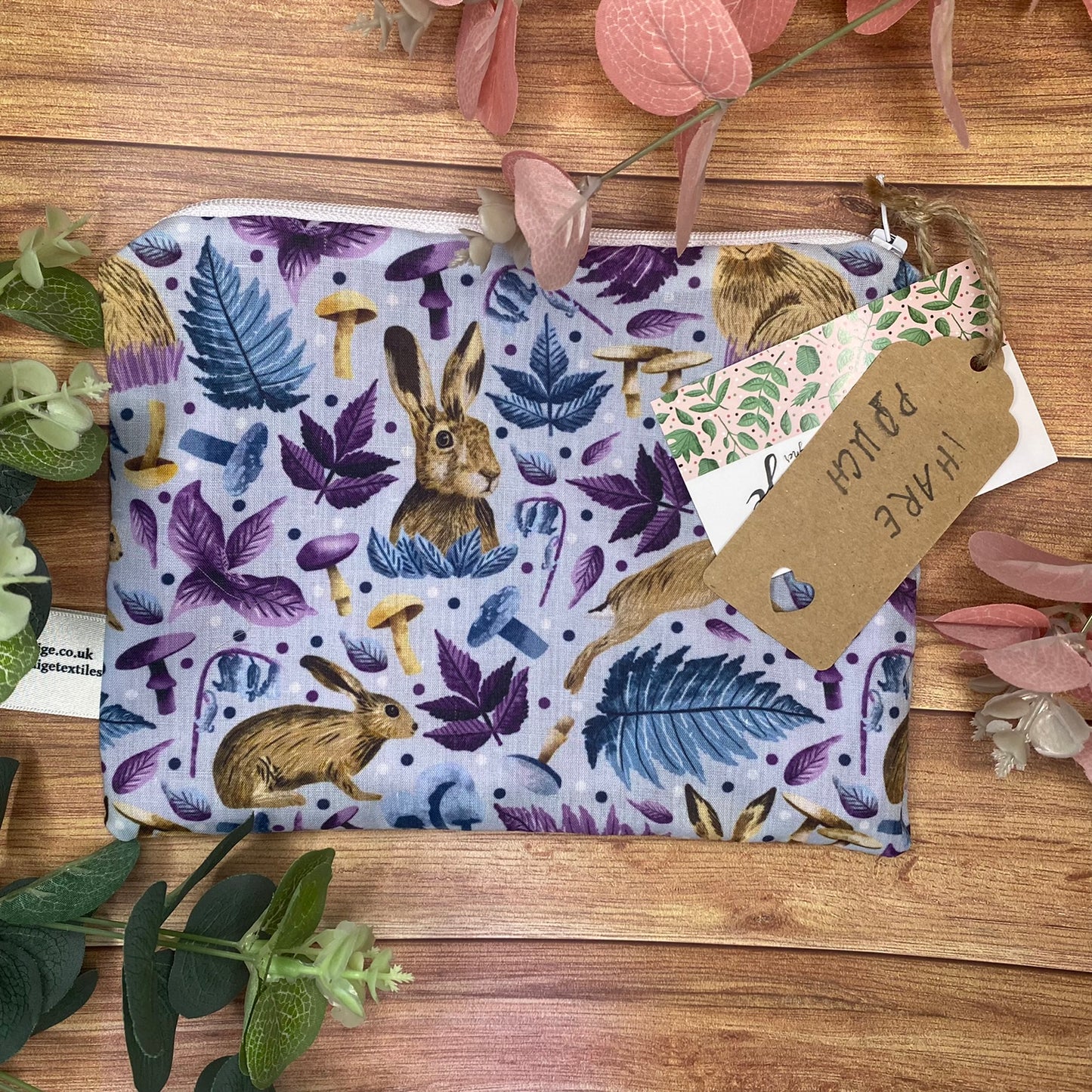 Pouch with a hare surface pattern design on a wooden surface with foliage