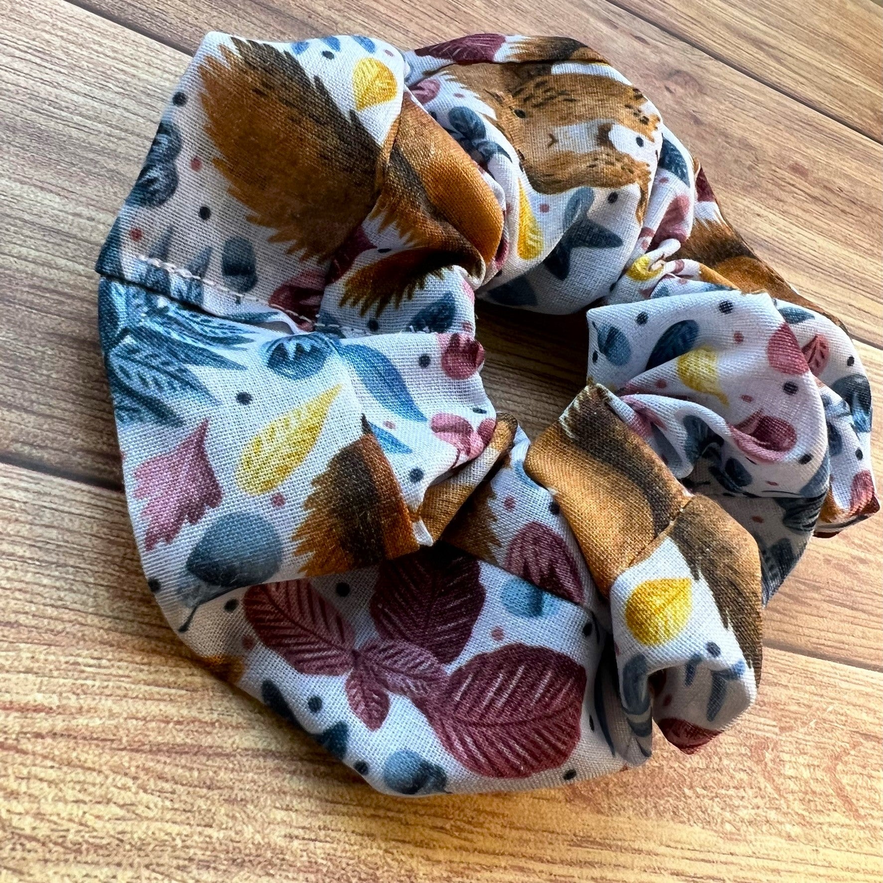 closeup of red squirrel patterned scrunchie on wooden backdrop