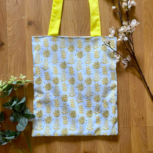 closeup of yellow foliage reusable shopping bag on a wooden background with foliage around it