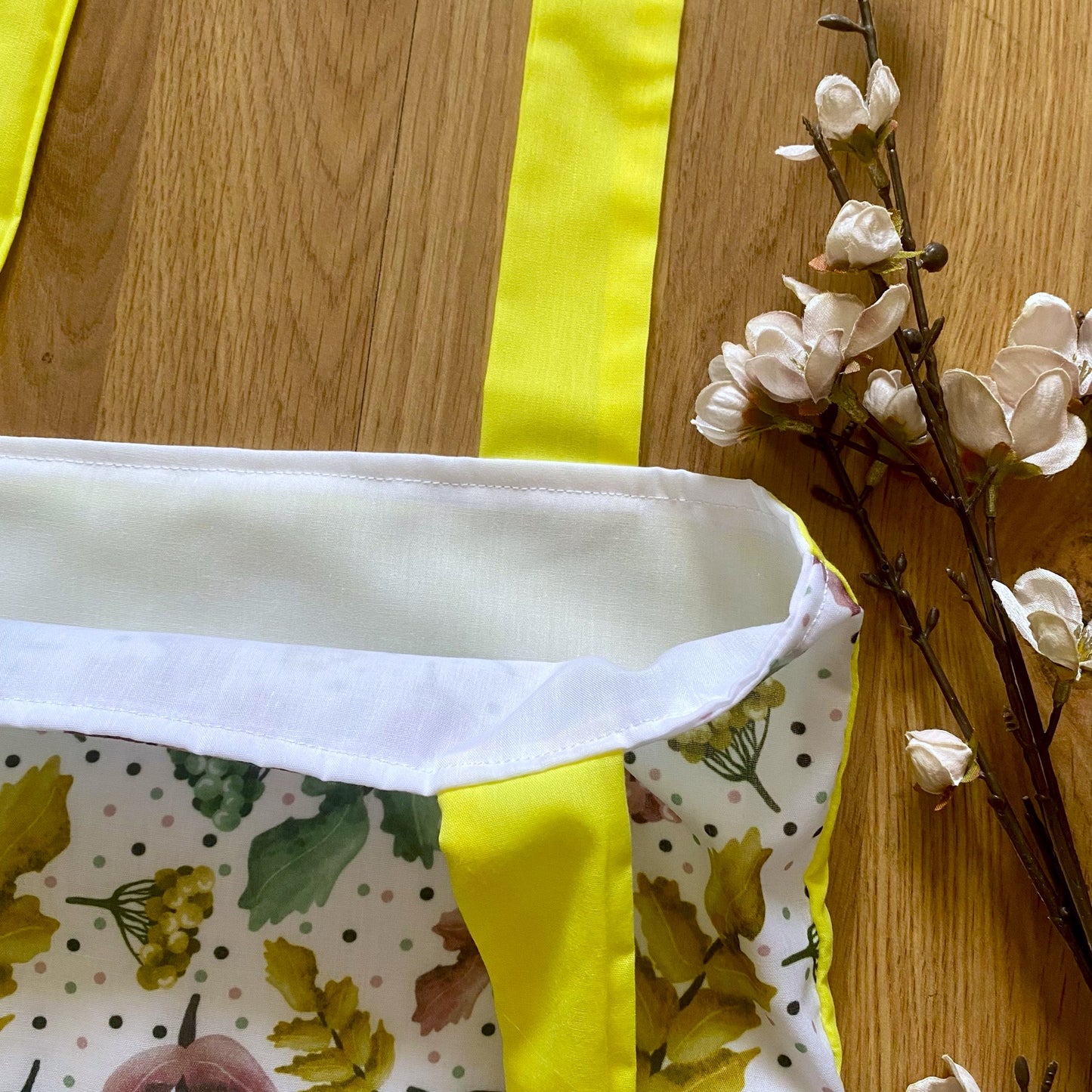 closeup of the corner of the pretty foliage tote bag showing the white lining inside and the yellow straps.