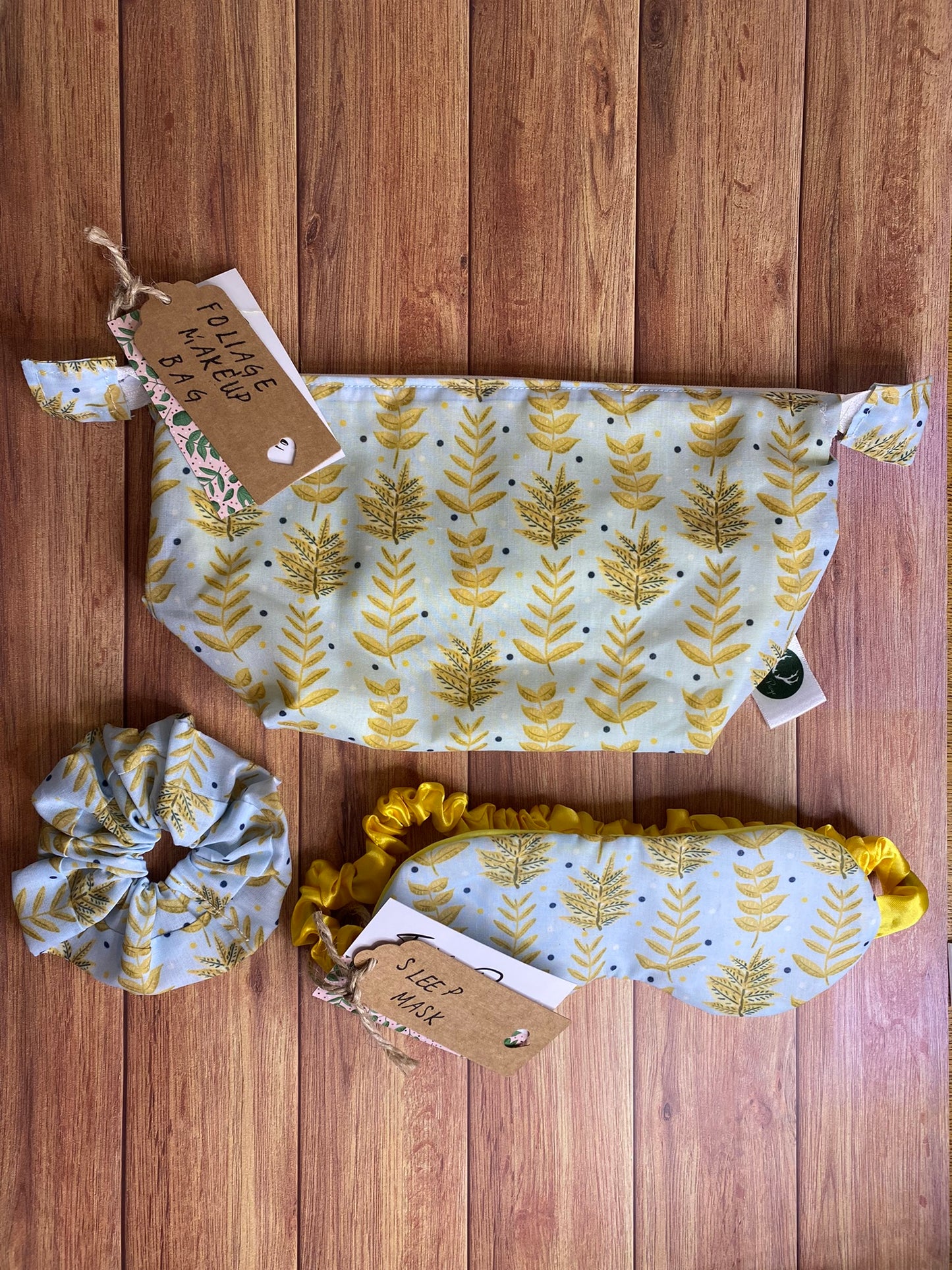 yellow foliage patterned makeup bag and sleepmask and scrunchie giftset on wood surface