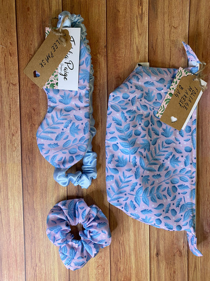 Blue foliage surface pattern design on a giftset including a makeup bag, sleepmask and a scrunchie, all sat on a wooden background
