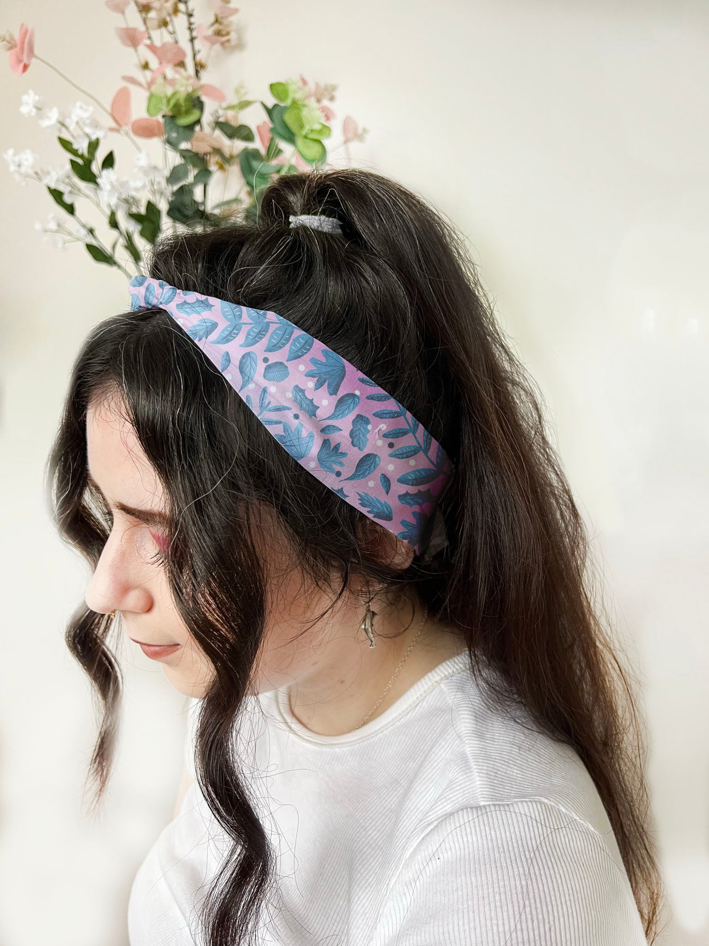 Photograph of dark haired girl wearing a headband with the blue foliage surface pattern design on it, this blue hair accessories is ideal for short hair with a cute leafy headband 