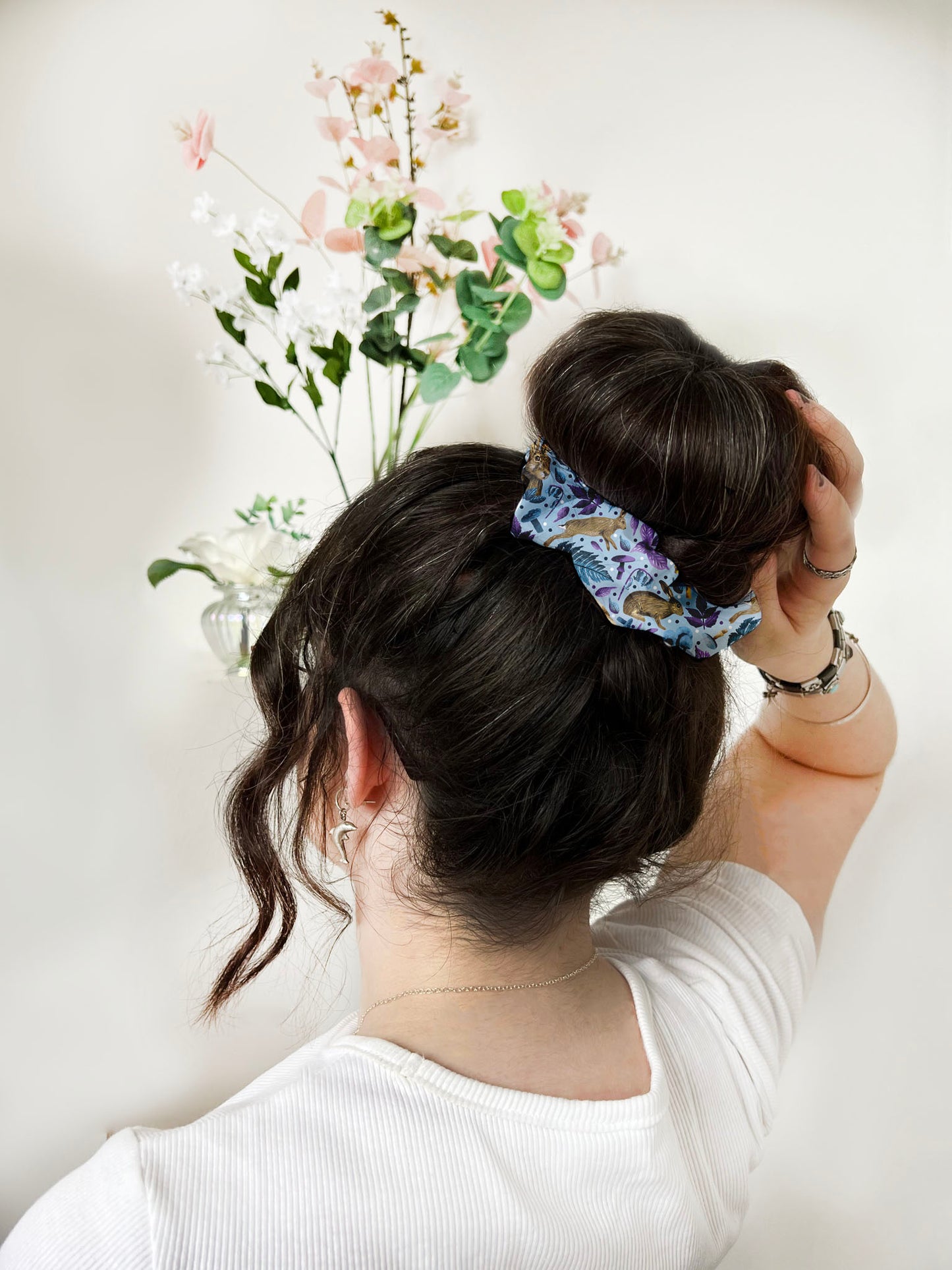 scrunchie with hare pattern on it around a bun on dark haired girl