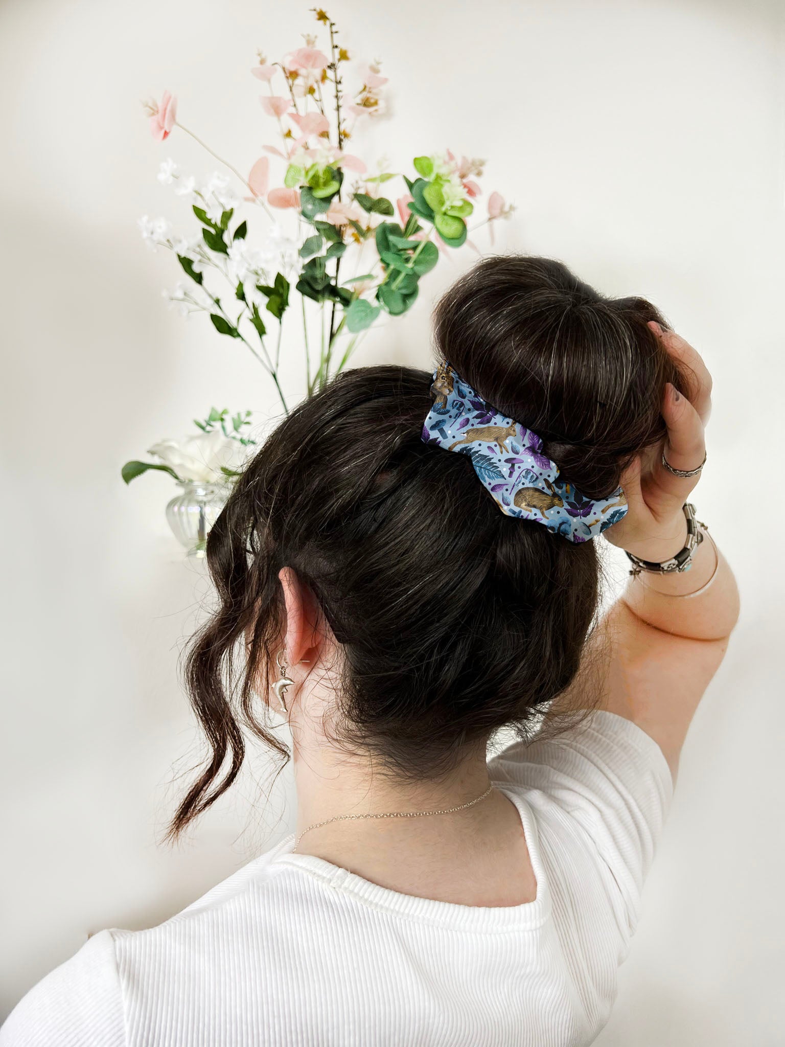 Dark haired girl photographed with a high bun, with a blue and purple patterned scrunchie holding it up.