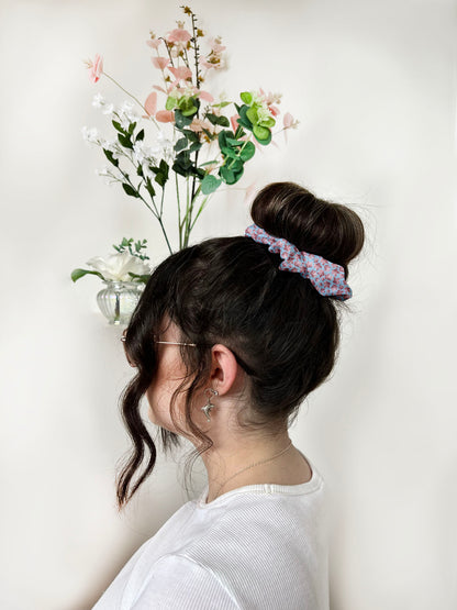 pink leafy patterned scrunchie around a bun on a dark haired girl's head