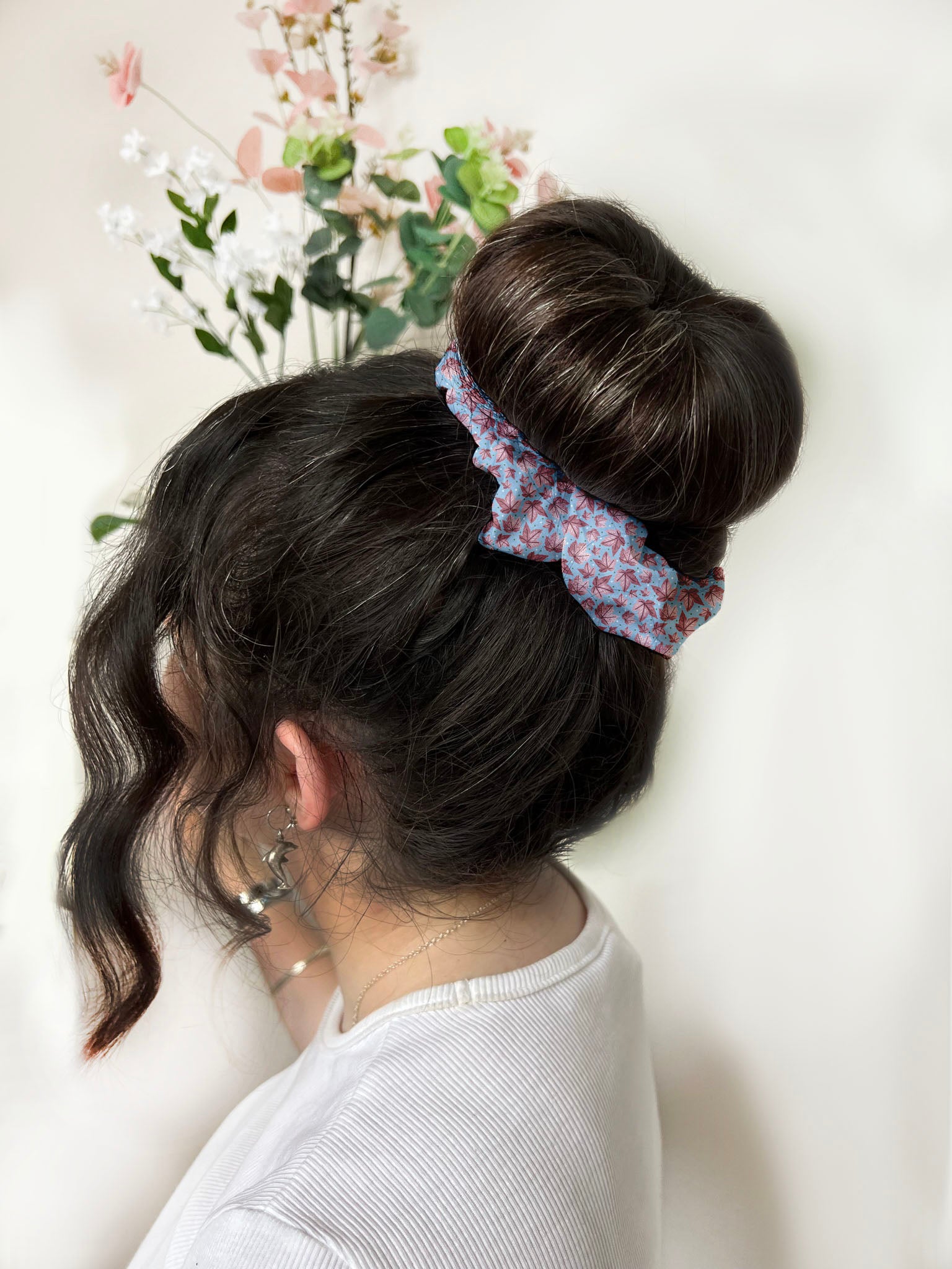 dark haired girl with bun and the pink leafy scrunchie around it